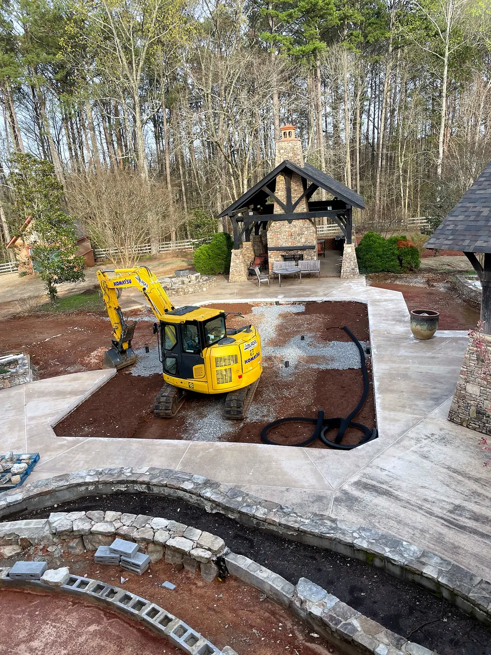 Mini excavator working inside the former swimming pool area during removal and backfill preparation.