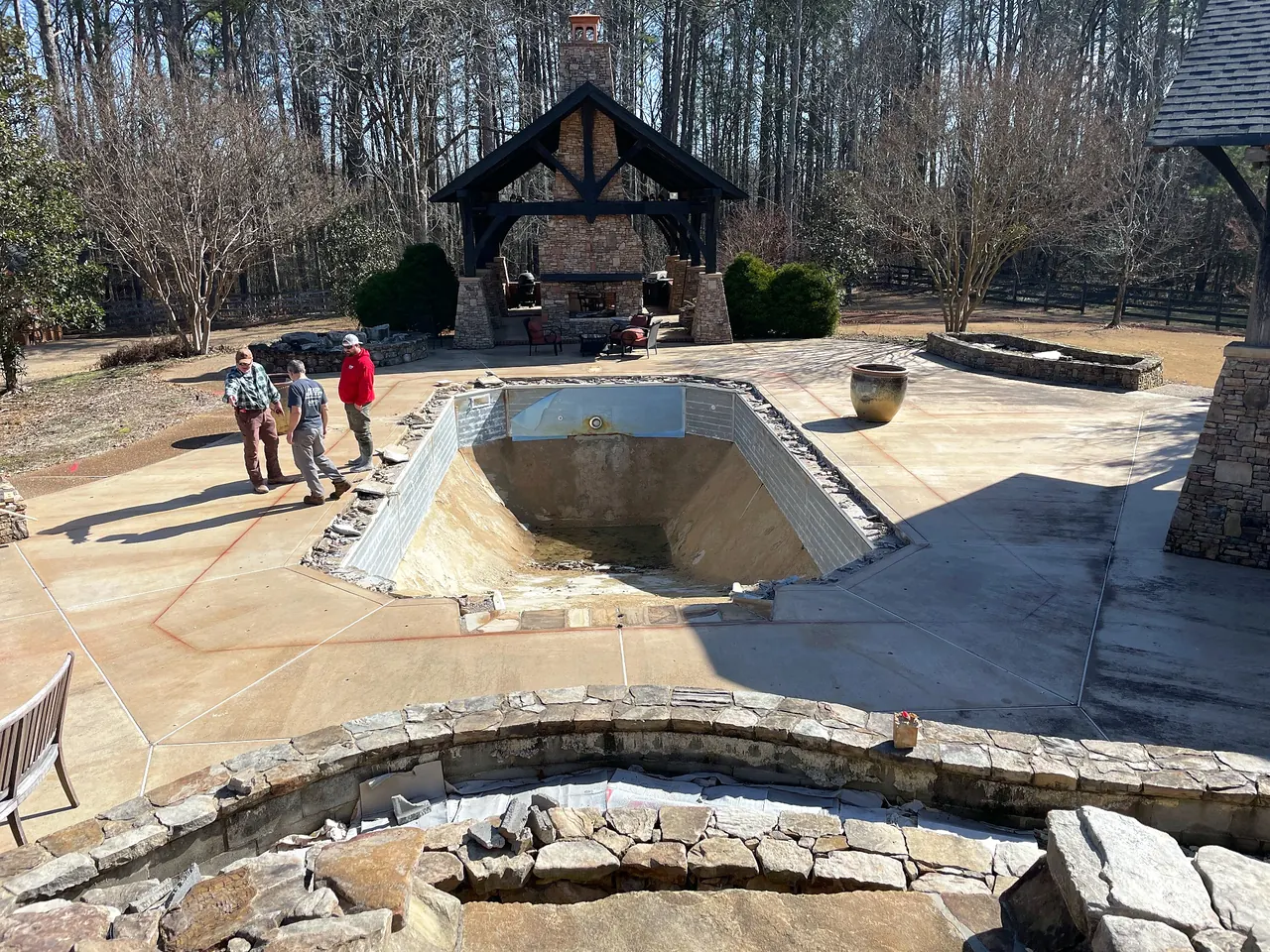 Swimming pool emptied and prepared for removal during a ranch property renovation.