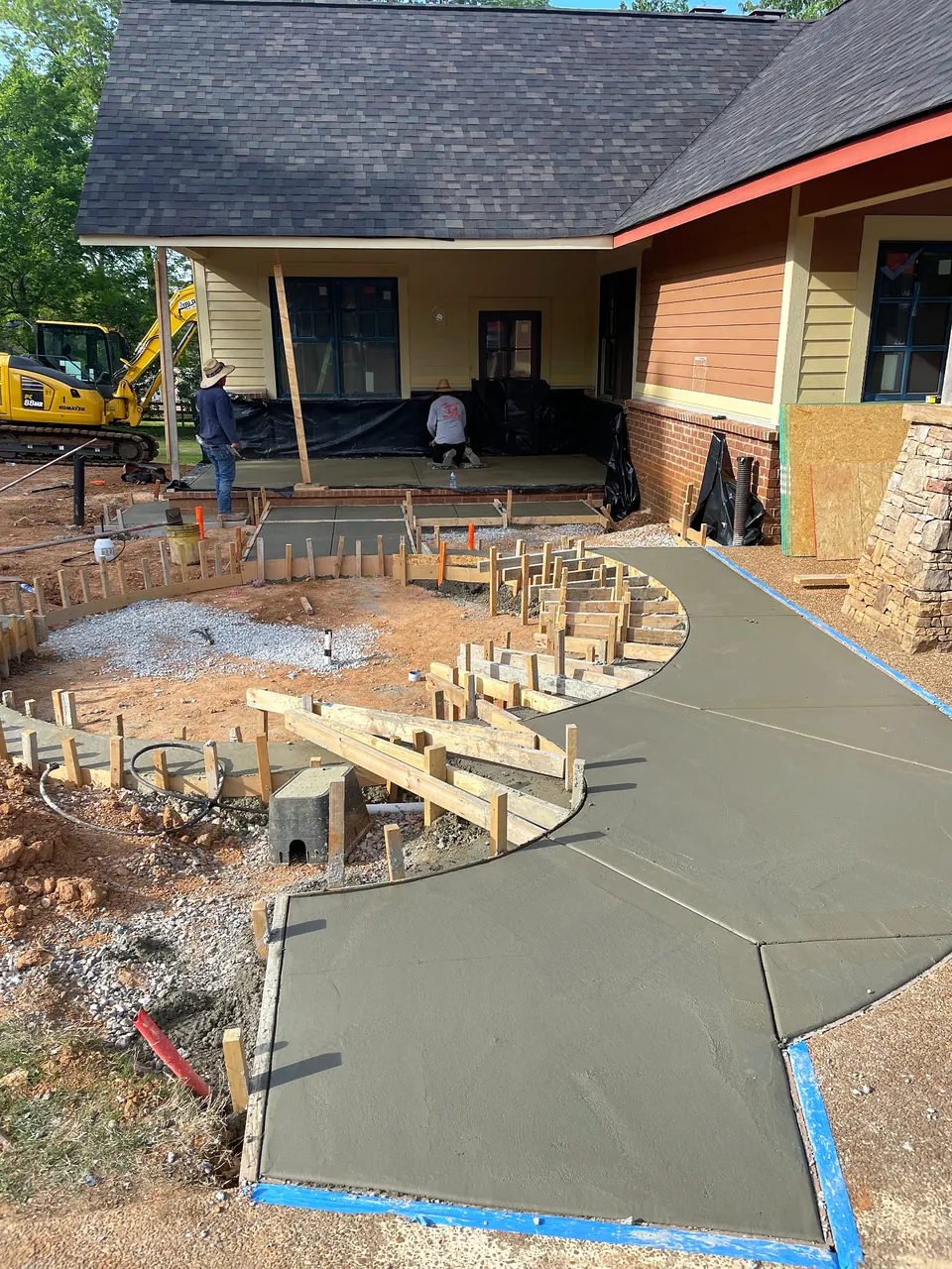 Curved concrete placement in progress during site preparation for a ranch house porch addition.
