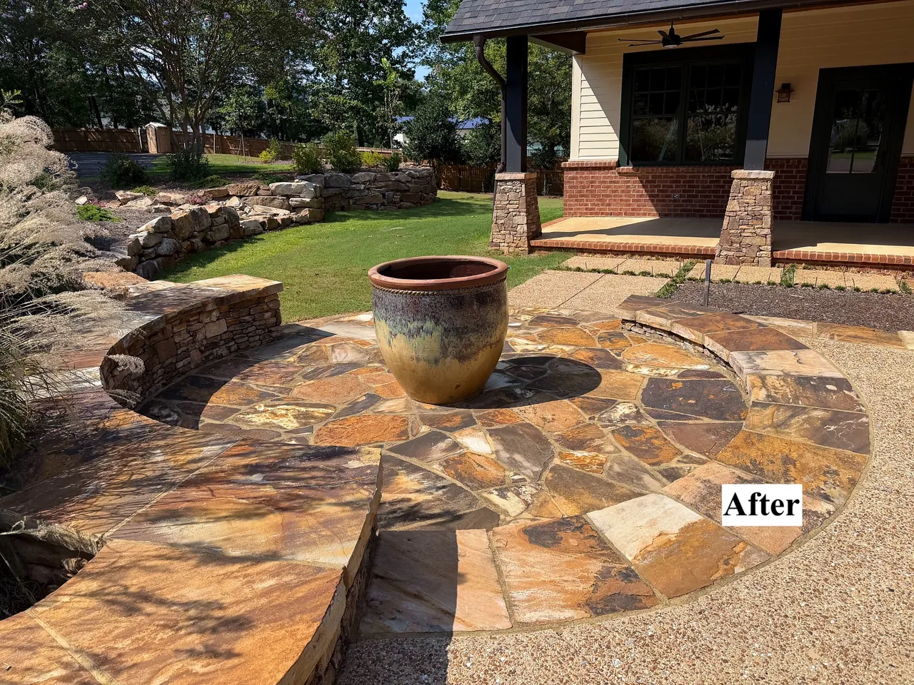 Completed porch addition with stone columns, curved hardscape, lawn and landscape stonework.