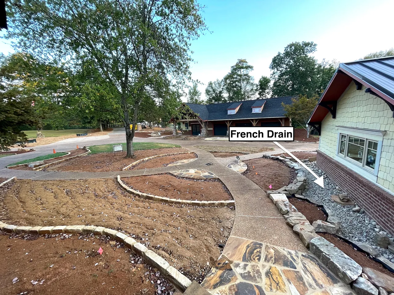 French drain installation integrated with walkways and landscape beds around a ranch residence.