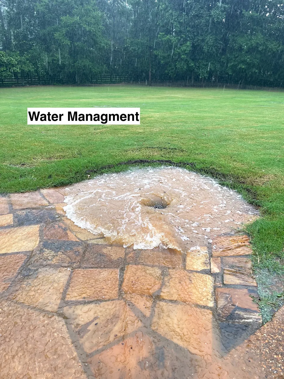 Surface water moving through a landscaped drainage outlet designed for water management on a ranch property.