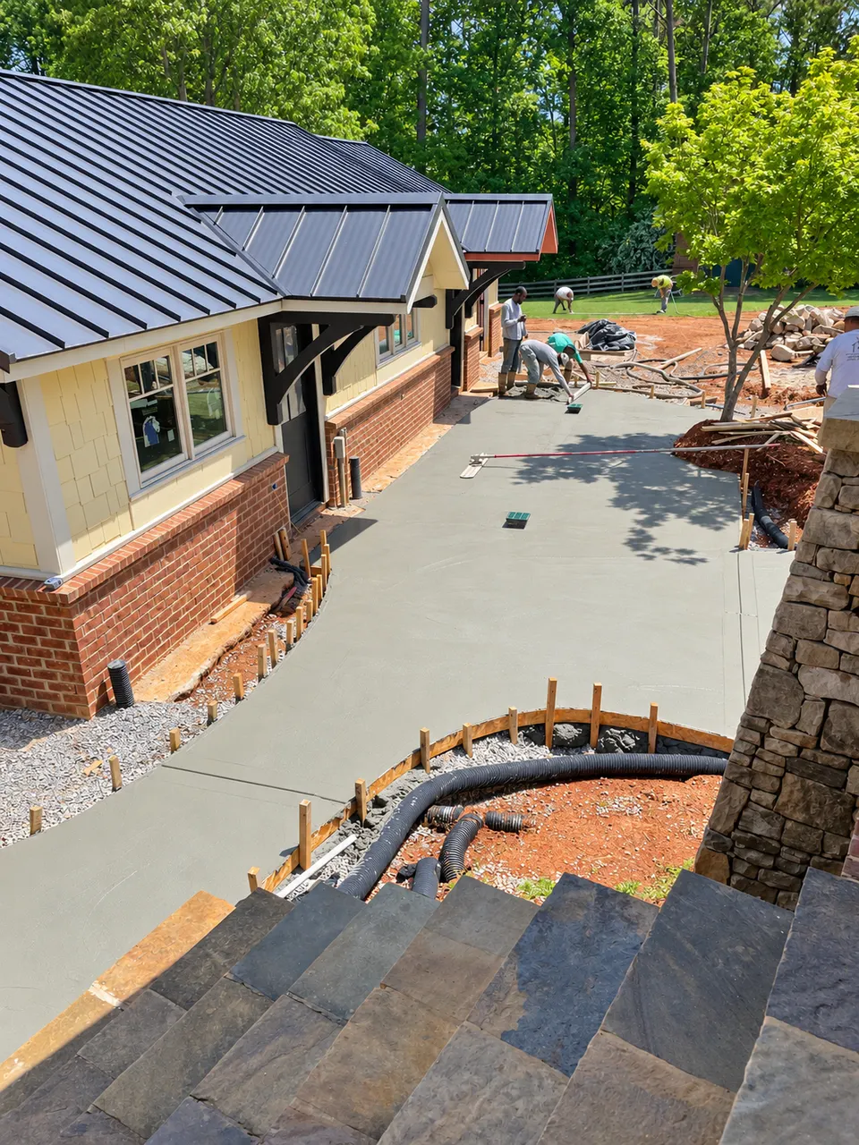 Curved concrete base prepared for a stone walkway with integrated site infrastructure.